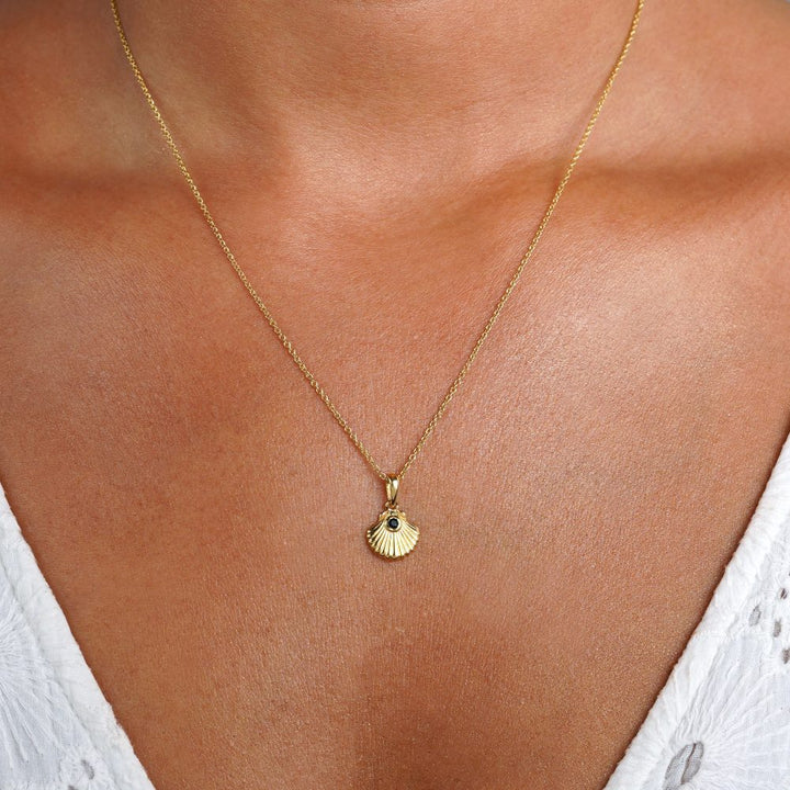 Zeeschelpenketting in goud met zwarte Onyx edelsteen. Kristallen ketting met Onyx in een gouden schelp.