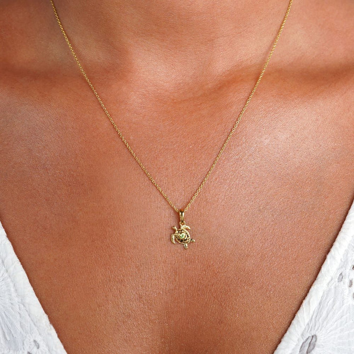 Gouden schildpadketting met een klein groen Peridot kristal. Edelstenen ketting in goud met een schattige schildpad en een kleine groene edelsteen Peridoot.