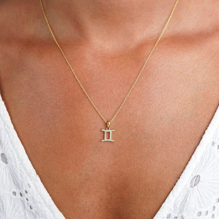 Gouden ketting met Gemini (Tweeling) symbool gevuld met White Topaas kristallen. Edelstenen ketting met Gemini (Tweeling) symbool dat schittert.